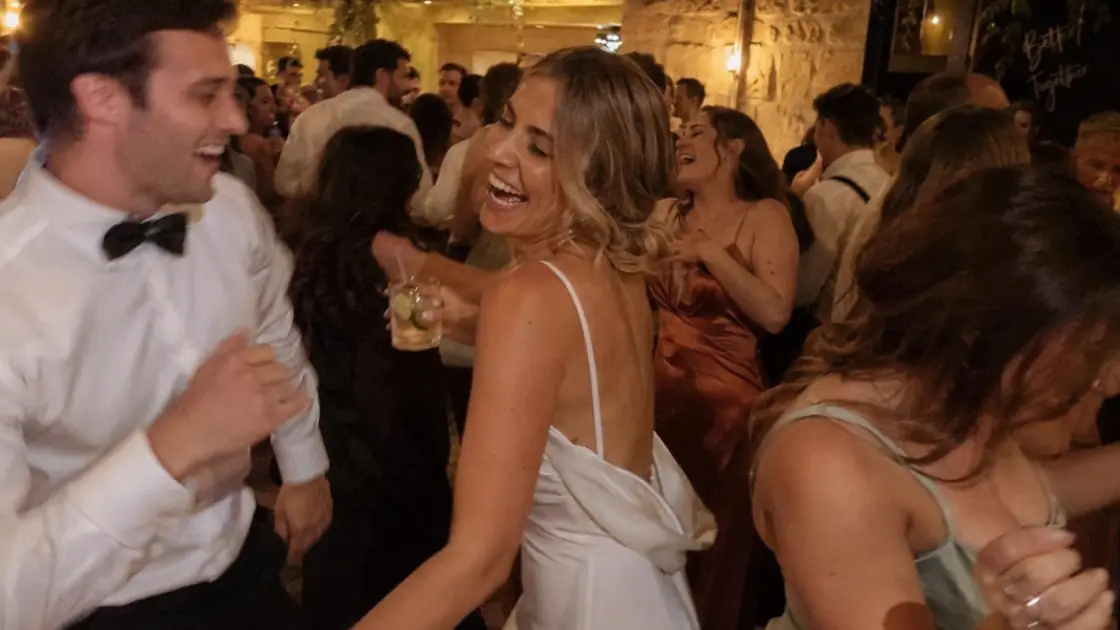A couple dancing among their guests under festoon lights