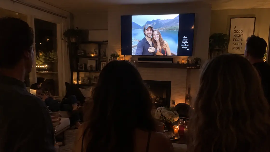 Friends on a couch watching photos on a lounge-room TV