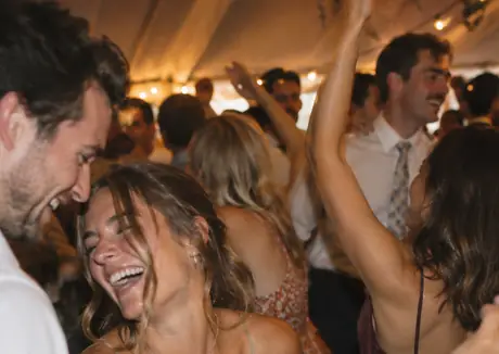 Two guests laughing together on a crowded reception floor
